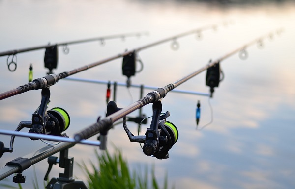 Three Fishing Rods With Professional Reel Set Up On The Lake.